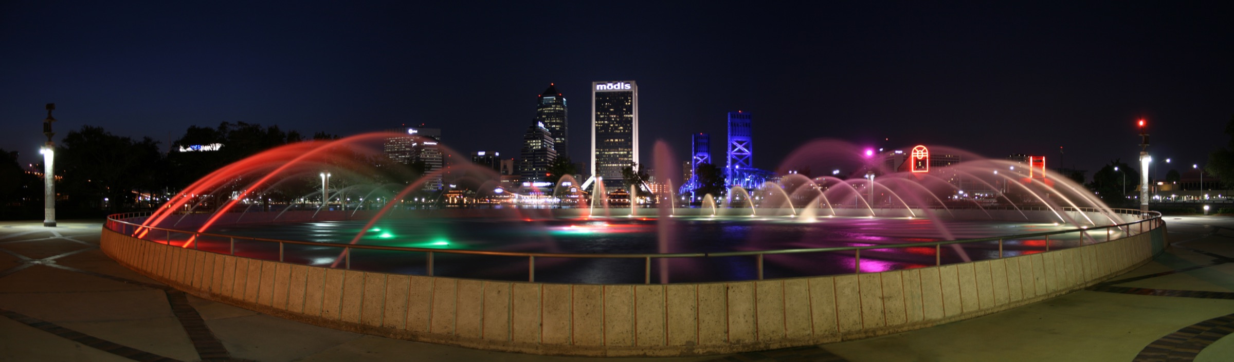 Friendship Fountain illuminated at night with the Jacksonville skyline beyond it