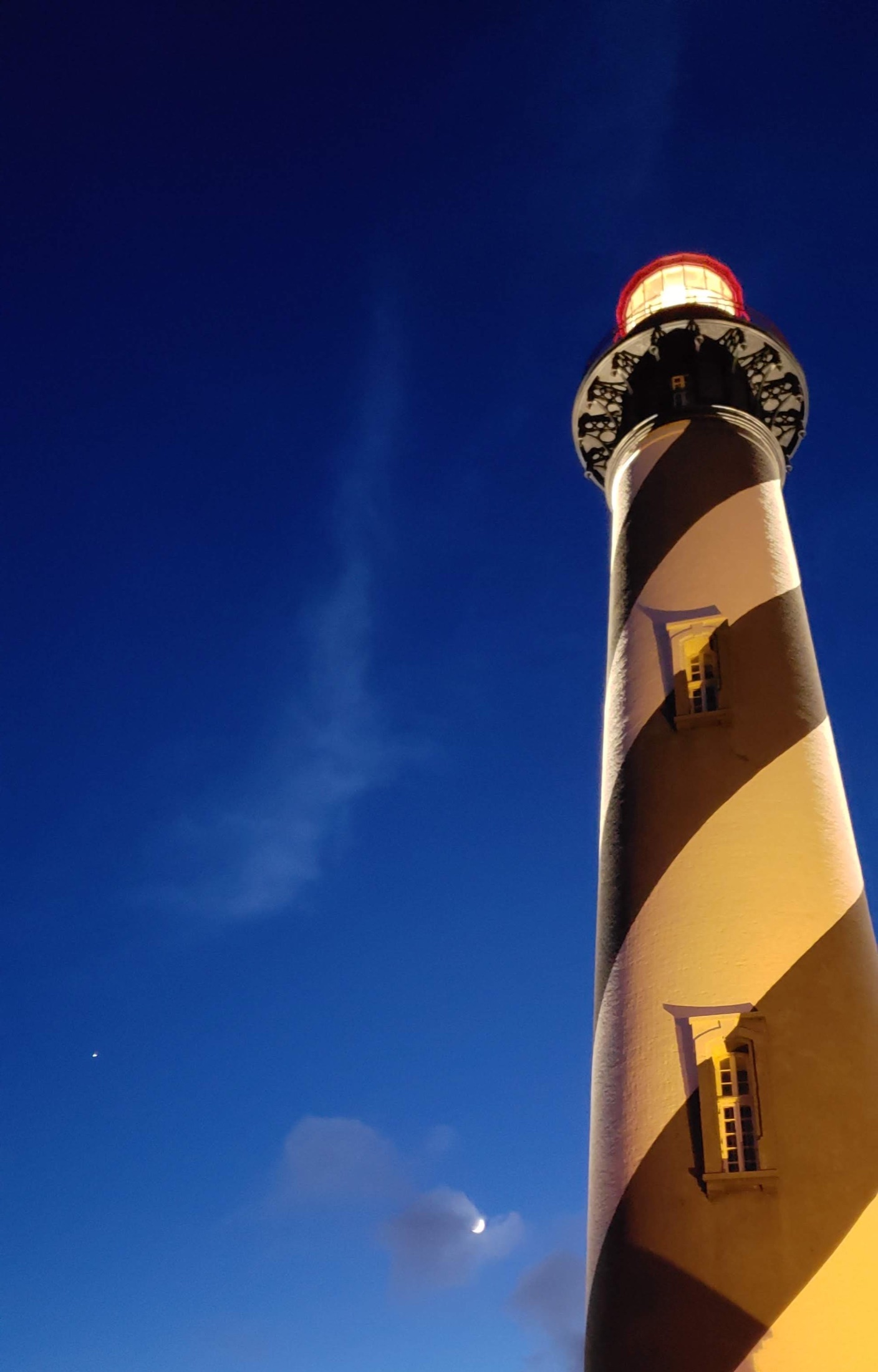 St. Augustine Lighthouse against a deep blue twilight sky and crescent moon